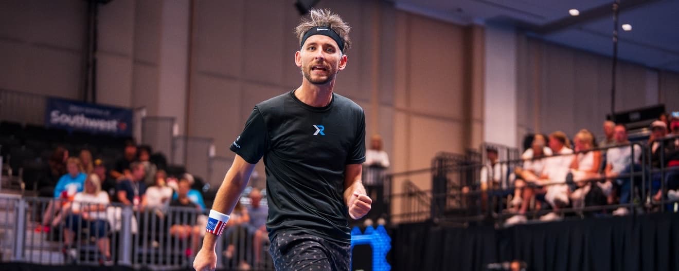 Eric Roddy mid-celebration in a black XR jersey and Nike headband, USA wristband, indoor arena crowd behind